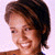 Pixelated close-up of a person's head and shoulders with short dark hair, light skin, and a faint smile against a pale background.
