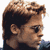 Pixelated static image of a person's head and shoulders in profile view with brown hair, visible ear, and dark clothing against white background.