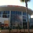 Pixelated static image of a building facade with large windows and a streetlamp, under a light sky.
