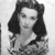 Black-and-white pixelated image of a person with shoulder-length dark hair, wearing a light-colored top with a patterned lower section, against a plain background.