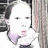 Pixelated static image of a person with light skin, dark hair tied back, wearing a white top and dark collar, positioned against a striped background.