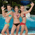 Group of people in swimwear posing by a pool with greenery background, transitioning from standing to reclining positions.