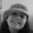 Black-and-white pixelated image of a person wearing a wide-brimmed hat and dark clothing, with visible facial features including eyes, nose, and mouth.