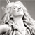 Pixelated grayscale image of a figure with long hair, closed eyes, and a neutral expression, wearing a light-colored garment with dark accents against a plain background.