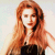 Pixelated image of a person with long reddish-brown hair wearing dark clothing against a light background.