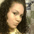 Pixelated close-up of a person with dark hair and light skin, wearing a light-colored top against a blurred background.