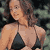 Static pixelated image of a woman in a bikini top with curly hair against a dark background.