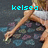 A pixelated image of a person sitting with legs crossed, wearing a white top and brown shorts, with cyan text above the head.