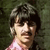 Pixelated image of a person with dark hair and light skin wearing a pink top against a dark green background.