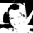 Black-and-white pixelated image of a person with dark hair styled in an updo, smiling and making a peace sign gesture with their right hand.