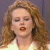 A static pixelated image of a person with long wavy light brown hair, closed eyes, and orange lips against a muted purple background.
