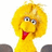Yellow bird-like character with large round eyes, red beak open in a smile, and fluffy yellow feathers against white background.
