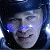 Pixelated face with blue and white highlights against dark background, showing partial features including eyes, nose, and mouth in low-resolution style.