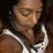 Pixelated close-up of a person with closed eyes wearing a white sleeveless top and dark necklace against a brown background.