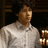 Pixelated image of a person in a light-colored shirt on a blue background with text elements.