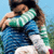 Two figures embrace in a pixelated static image with blue sky and green foliage background.
