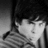 Pixelated grayscale image of a figure with light-colored hair and dark clothing, partially obscured by low resolution.