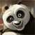 Pixelated panda face with black ears, eye patches, and nose, white fur, green pupils, brown mouth, and pink tongue visible, set against blurred background.