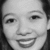 Black-and-white portrait of a smiling person with dark hair, cropped to show head and shoulders against light background.