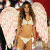 A woman with long brown hair wearing a white bikini top and bottom, standing against pink wings and red background.