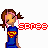Pixel art of a girl with brown pigtails and pink hair ties wearing a blue shirt with red and yellow Superman logo, standing against white background.