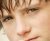 A pixelated close-up of a person's face showing eyes, nose, and mouth with brown hair visible on the left side.