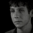 Pixelated grayscale portrait of a person with short dark hair, neutral expression, and visible neck against black background.