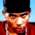 Pixelated close-up of a person wearing a black cap and red garment against a light blue background.