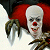 Static pixelated image of a clown face with red nose and white makeup, partially obscured by dark green foliage against a bright background.