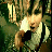 Pixelated static image of a character with light hair and dark clothing against a green background, holding an object.