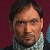 Static 50x50 pixel icon showing a close-up of a person's face with dark hair and light skin, wearing a white collared shirt against a maroon background.