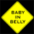 Yellow diamond-shaped sign with pixelated text reading "BABY IN BELLY" on a black background.