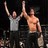 Two pixelated figures with raised arms against a dark background, one in light clothing, the other shirtless.