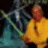 Pixelated static image shows two figures with one in yellow clothing and another in blue-green tones against dark background.