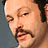 A static image of a man with a mustache against a gray background, with red bars and text at the bottom.