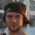 Static 50x50 pixel icon showing a person with dark hair wearing a black cap and white shirt against blurred background.