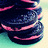 Pixelated image of stacked dark blue cookies with pink stripes on left, bright pink background with white pixelated text on right.