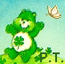 Green Care Bear with white belly holding four-leaf clover, standing on grassy mound under light blue sky with butterflies and 'P.T.' text.