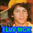 A pixelated image of a person with curly brown hair wearing a yellow hat and shirt, with a blue banner displaying text at the bottom.