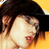 A pixelated close-up of a person with dark hair wearing a black hat, light skin, and red lips against a yellow background.
