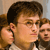 Three people with brown hair appear in a pixelated image; the central figure wears glasses and a light-colored shirt, with two others partially visible behind.