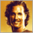 Pixelated portrait of a smiling person with curly hair against warm yellow background, adjacent to golden 'SAHARA' text on dark brown backdrop.