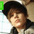 A pixelated image of a person wearing a black cap and dark jacket, with text overlays changing across frames.