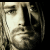 A static image featuring a black background with white text and a grayscale portrait of Kurt Cobain, displaying the phrase "A Legend Dies Never" above his name and lifespan dates.