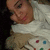 Pixelated image of a person with light skin wearing white clothing and brown pants, holding a game controller with colored buttons.