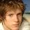 Pixelated close-up of a person with light brown hair and fair skin, set against a blurred beach background.