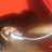 A pixelated image shows a dark brown curved shape above a light beige surface with white highlights, set against an orange-red background.