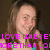 Pixelated image of a person with long brown hair wearing a colorful top, overlaid with bright pink text reading "LOVE LINDSEY MORE THAN JOY" against a dark background.