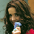 A pixelated close-up of a person with long dark hair holding a small blue and white object against a blurred background.