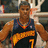 Pixelated image of a basketball player in dark blue jersey with yellow number 7 and orange text, standing on court with arms outstretched against black background.